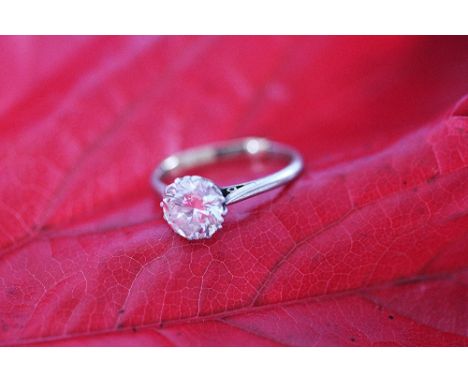 A diamond and platinum solitaire diamond ring, the round brilliant cut diamond within claw setting and white metal hoop

With