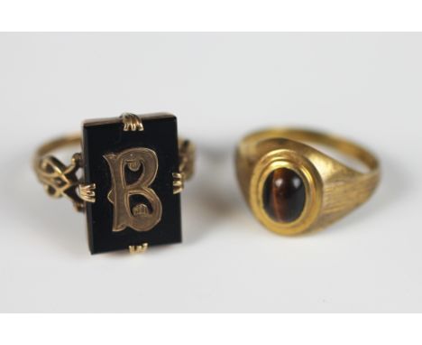 A tigers eye set signet ring, set in 9ct yellow gold and a gold and onyx 'B' set ring, total weight 7.6gms (2)