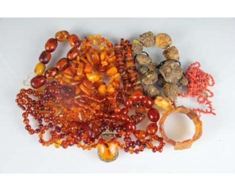 A collection of amber and amber coloured beads and necklaces, along with a stick coral necklace and a simulated amber pendant