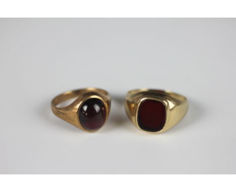 A garnet set gold ring, the cabochon garnet within yellow gold setting stamped '9ct' and a hardstone set signet ring set in 9