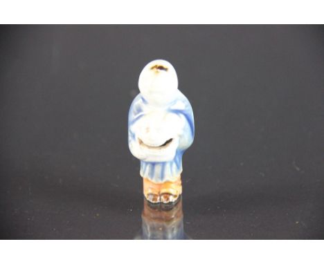 A Chinese porcelain netsuke, modelled as a male figure holding a mask, the mask with open mounth enclosing a bead, 6cm