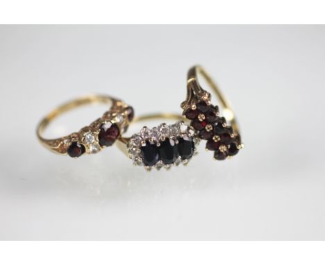 A sapphire and diamond triple cluster ring set in 9ct gold and two garnet set dress rings, also set in 9ct yellow gold, total