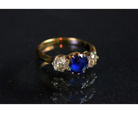 A sapphire and diamond three stone ring, early 20th century, the two old cut diamonds flanking a central circular sapphire, a