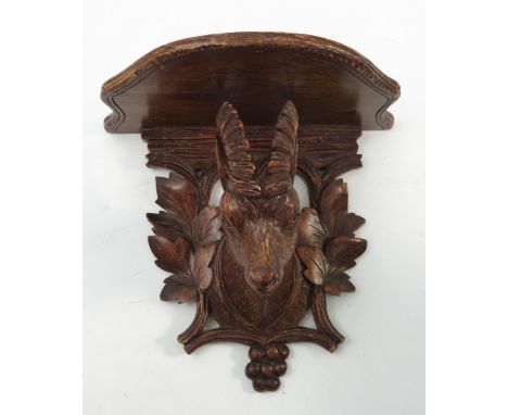 A 19th century Black Forest carved wall bracket, the shaped shelf supported by a stag head with leaf, grape and scroll back, 