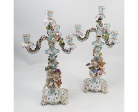 A pair of 19th century Continental porcelain four light candelabra, ornately modelled with two children, moulded with scrolli