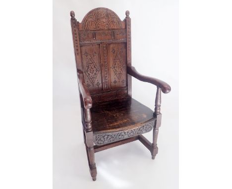 A late 17th century oak arch carved and panel back chair with solid seat and turned supports 
