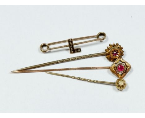 A 15 carat gold stick pin set ruby, a similar yellow metal stick pin, a yellow metal plain stick pin and a 9 carat gold 'L' b