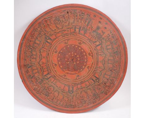An Oriental circular red lacquer papier mache panel decorated with peacock and immortals, 46cm diameter 