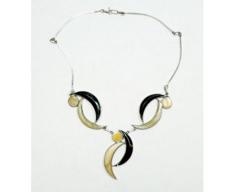 A vintage white metal necklace with mother of pearl and black enamel crescent design in a vintage necklace case 