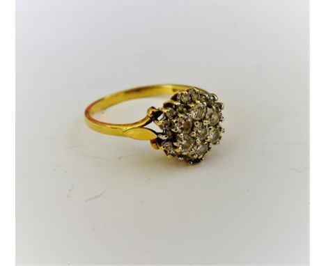 An 18ct gold and diamond cluster ring, claw set with the seven principal circular cut diamonds to the centre, in a surround o