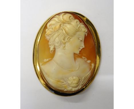 A 9ct gold mounted large oval shell cameo brooch, designed as the portrait of a lady with a flower, Birmingham probably 1987.