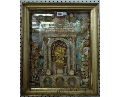 An early 20th century wall mounted shrine, depicting a gilt metal Jesus under a silk and beadwork arch over an altar decorate