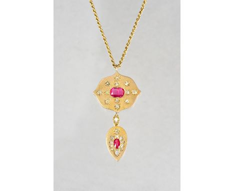 A gold, ruby and diamond set pendant, with a shaped oval top centered by an oval cut ruby and otherwise set with twelve cushi