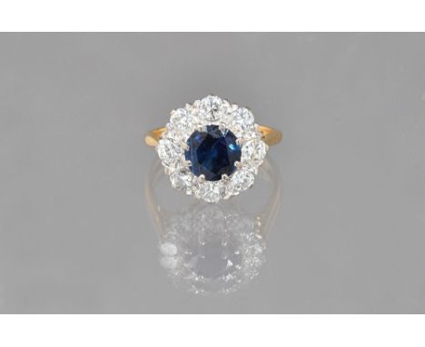 An 18ct gold, sapphire and diamond cluster ring, claw set with the circular cut sapphire at the centre, in a surround of eigh