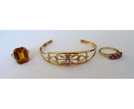 A gold ring, claw set with a cut cornered rectangular step cut citrine, a gold ring, mounted with a row of three cushion shap