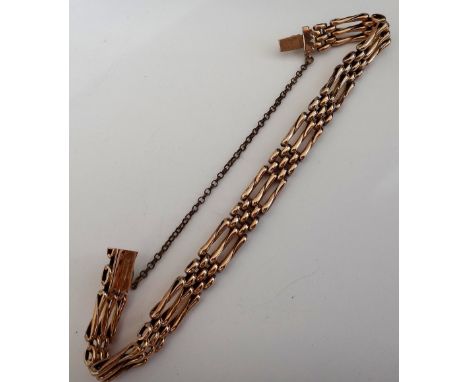 A gold oval and twisted bar link gate bracelet, on a snap clasp, detailed 9 CT, fitted with a base metal safety chain, gross 