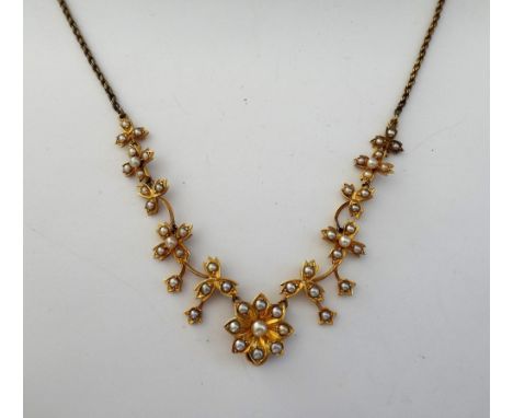 A gold and seed pearl set necklace, in a graduating floral and foliate openwork design, mounted with half pearls, on a ropetw