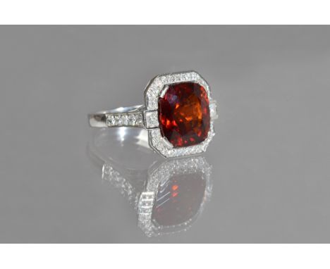 An 18ct white gold, diamond and garnet cluster ring, mounted with the large cushion shaped garnet to the centre, in a surroun