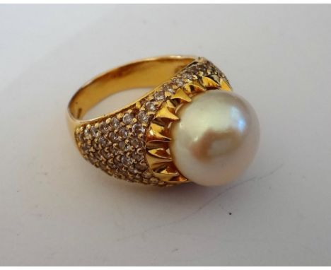 A gold, cultured pearl and colourless gem set ring, mounted with the cultured pearl to the centre, between colourless gem set
