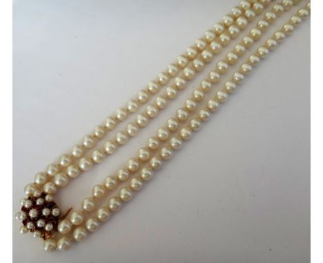 A two row necklace of uniform cultured pearls, on a gold, cultured pearl and ruby set clasp, detailed 14 K..