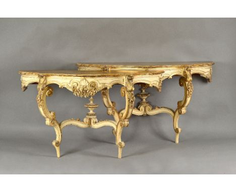 A pair of 19th century Baroque Revival parcel gilt cream painted carved wood console tables, on opposing 'C' scroll supports,