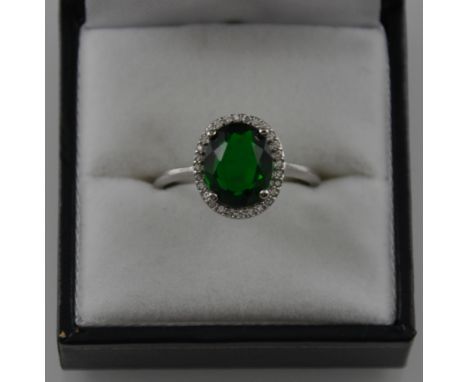 A silver cubic zirconia and green stone ring