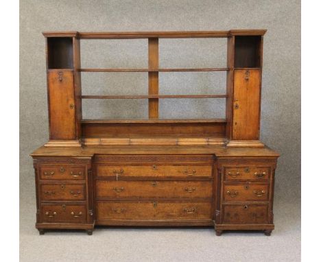 A GEORGIAN OAK AND MAHOGANY BANDED LARGE DRESSER of inverted breakfront form, late 18th century and later, the delft rack wit