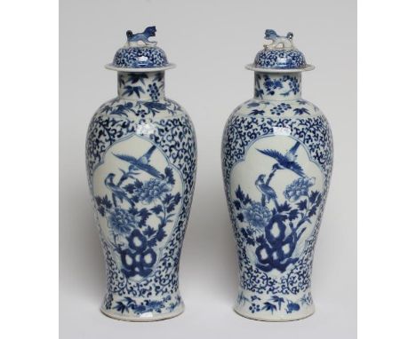 A PAIR OF CHINESE PORCELAIN VASES AND COVERS of inverted baluster form, painted in underglaze blue with panels of birds amids