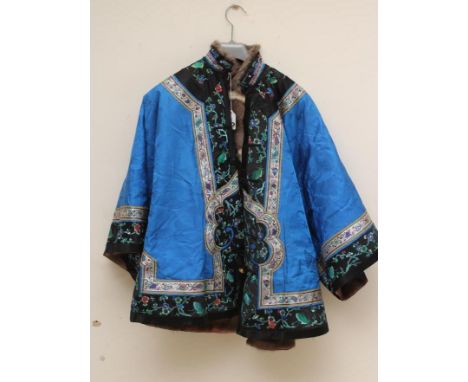 A CHINESE FUR LINED SILK JACKET, the insect woven blue silk damask with coloured silk embroidered black borders, the pink sil