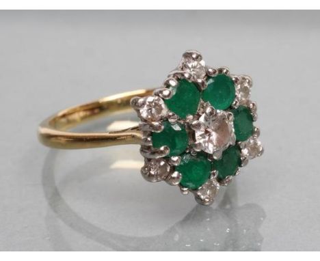 A DIAMOND AND EMERALD CLUSTER RING, the central diamond of approximately 0.20cts claw set to a border of six round cut emeral