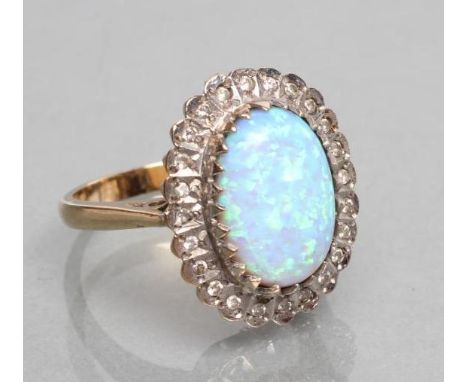 A SYNTHETIC OPAL AND DIAMOND COCKTAIL RING, the oval cabochon polished opal set to a border of numerous small diamonds to a p