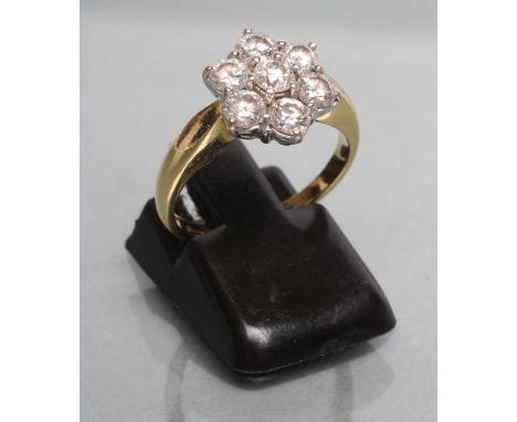 A SEVEN STONE DIAMOND CLUSTER RING, the point set stones on plain shoulders and gold shank, size K (Est. plus 21% premium inc