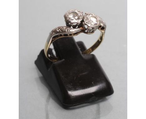 A TWO STONE DIAMOND RING, each stone of approximately 0.25cts in a rub-over cross over setting to diamond point set shoulders