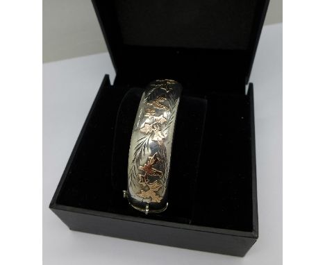 A silver bangle with gold overlay