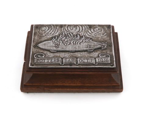 By Omar Ramsden and Alwyn Carr, an Arts and Crafts aluminium and oak Zeppelin paperweight, 1916, rectangular form, mounted wi