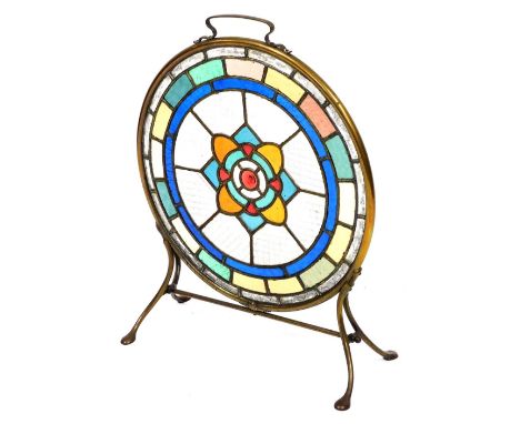 An Art Nouveau fire screen, inset with a circular stained glass panel of roundels, rectangles, etc., in coloured and textured