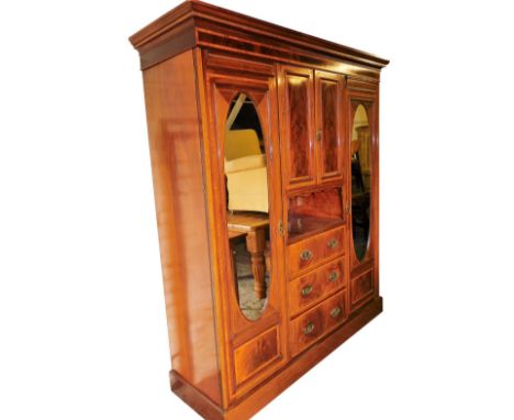 An Edwardian flame mahogany compactum wardrobe, with satinwood crossbanding and boxwood line inlay, the outswept pediment wit