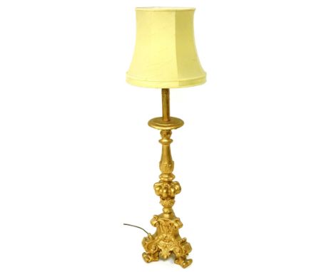 A Continental gold painted table lamp, with a beige shade, brass fitting and simulated candle support, the base modelled in t