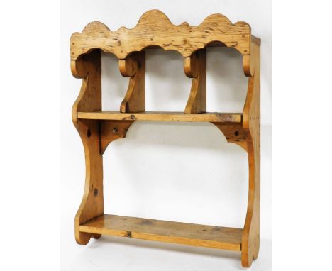 A pine wall mounted display rack, with a shaped top above three recesses above a single shelf, 70cm high, 51cm wide. 