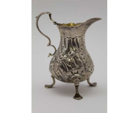 WILLIAM KERSILL, AN EARLY GEORGE III SILVER CREAM JUG, the body floral embossed, with c-scroll handle, raised on three trefid