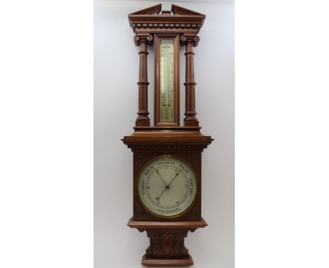 A LATE VICTORIAN WALNUT CASED ANEROID BAROMETER THERMOMETER, the case with dentil architectural pediment with columns on carv