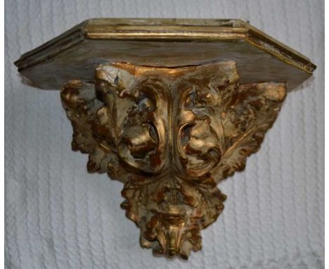 AN EARLY 20TH CENTURY WALL BRACKET acanthus leaf design in moulded plaster with wooden top, gilded and painted, 25cm high, th