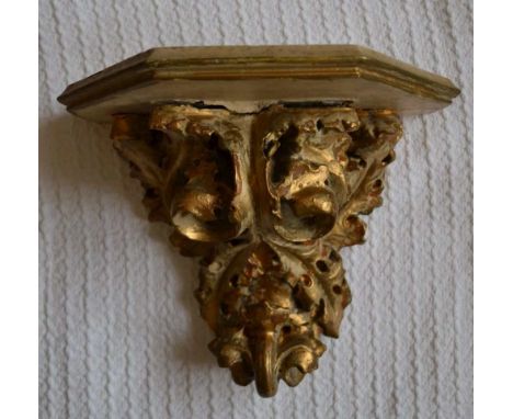 AN EARLY 20TH CENTURY WALL BRACKET, acanthus leaf design in mould plaster, with wooden top, gilded and painted 25cm high, the