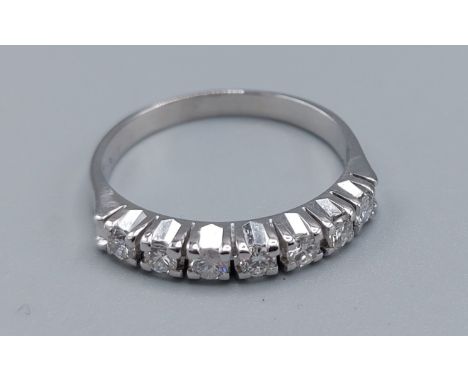 A 14ct white gold diamond set band ring, set with seven diamonds within a pierced setting, ring size R, 3.2gms 