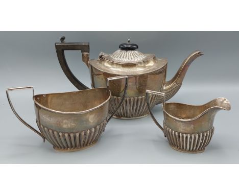 An Edwardian silver three piece tea service of half lobed form, comprising teapot, Birmingham 1903 and cream jug and sucrier,