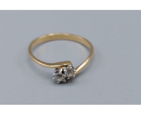 An 18ct gold two stone diamond ring, the two diamonds in a cross over setting, 1.6gms, ring size K 