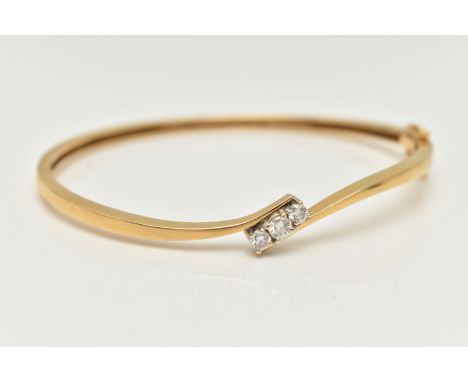 AN 18CT GOLD DIAMOND HINGED BANGLE, a polished bangle of cross over design, set with three round brilliant cut diamonds, each