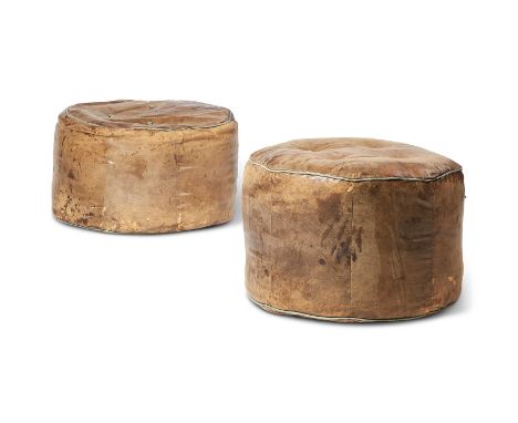 TWO SIMILAR DISTRESSED LIGHT BROWN HIDE POUFFESOf circular form, with sky blue pipingApproximately 40cm highProvenance: Suppl
