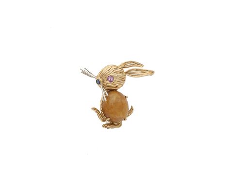 A jade and 18 carat gold brooch by Cartier, in the form of a rabbit, composed of an oval cabochon-cut jade to centre, the eye