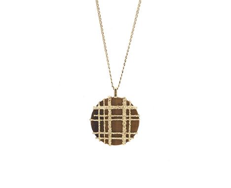An 18 carat gold and tiger’s eye pendant by Dunhill, Paris, composed of a large circular plaque of tiger’s eye with overlaid 